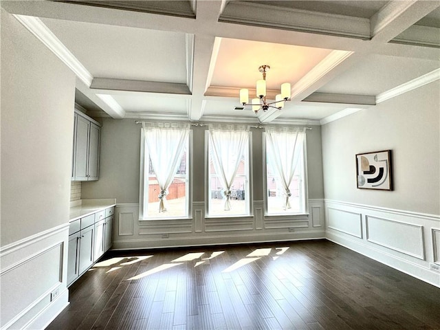 unfurnished dining area featuring a chandelier, dark wood-style floors, beam ceiling, and coffered ceiling
