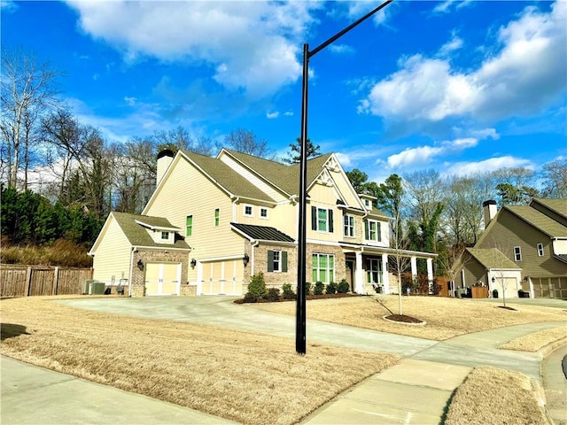 view of front of home with cooling unit, fence, a standing seam roof, a garage, and brick siding