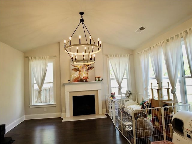living area with visible vents, baseboards, a notable chandelier, wood finished floors, and vaulted ceiling