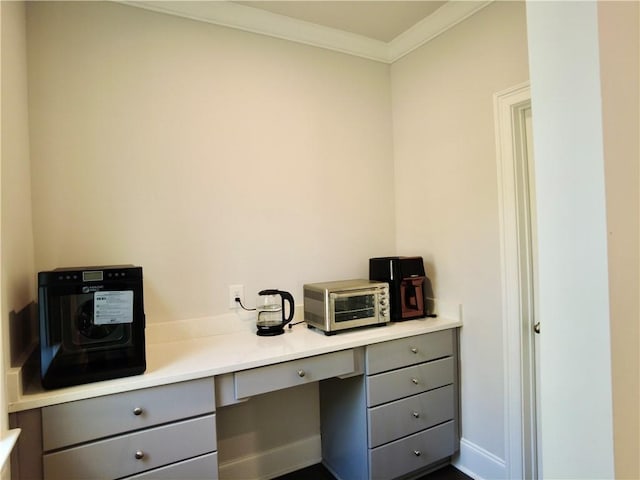 office space featuring built in study area, baseboards, ornamental molding, and a toaster