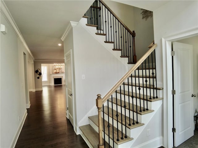 staircase with baseboards, ornamental molding, recessed lighting, a fireplace, and wood finished floors