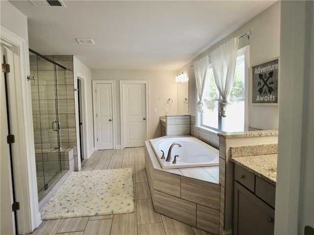 full bathroom with a shower stall, vanity, visible vents, and a bath