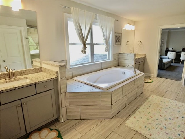 full bath with two vanities, a bath, and a sink