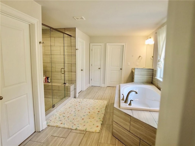 full bath with visible vents, wood finish floors, a stall shower, and a garden tub