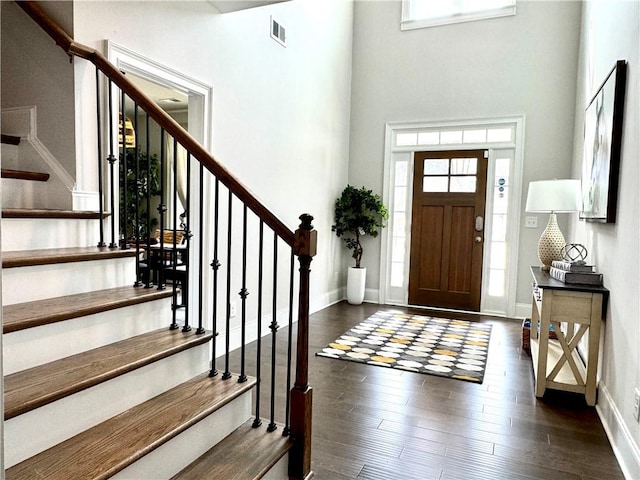 entryway with dark wood finished floors, a wealth of natural light, visible vents, and stairs