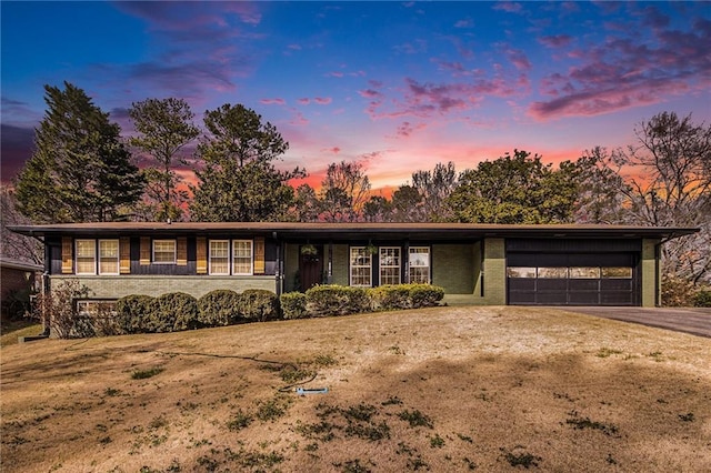 mid-century home with driveway, brick siding, and an attached garage