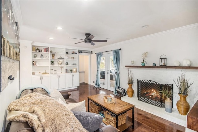 living area with french doors, a brick fireplace, dark wood-style flooring, and crown molding