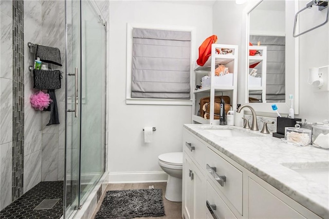 bathroom with a shower stall, baseboards, toilet, double vanity, and a sink