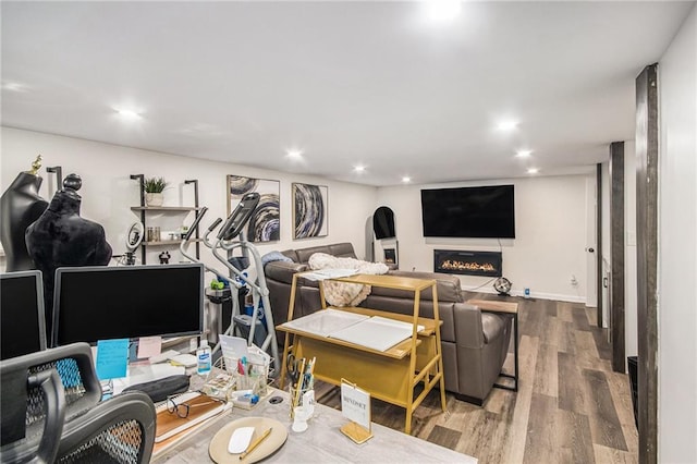 interior space featuring recessed lighting, a warm lit fireplace, and wood finished floors