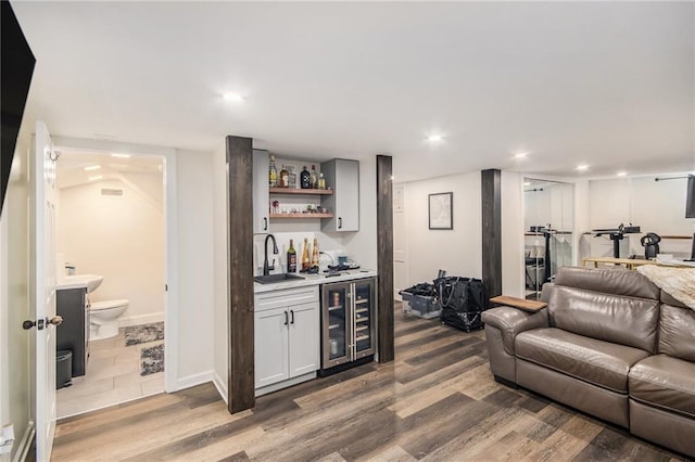 bar featuring wine cooler, recessed lighting, wet bar, wood finished floors, and a sink