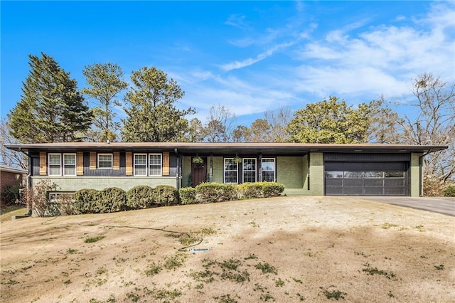 view of front facade featuring driveway, brick siding, and an attached garage