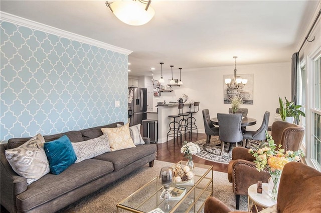 living room with wood finished floors, ornamental molding, an accent wall, and wallpapered walls