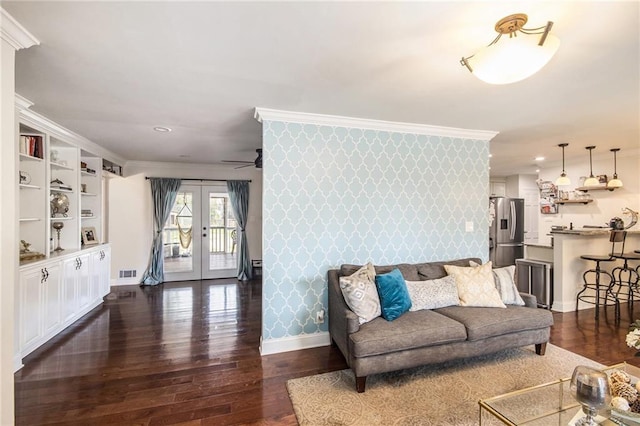 living room with dark wood-style floors, wallpapered walls, an accent wall, and ornamental molding