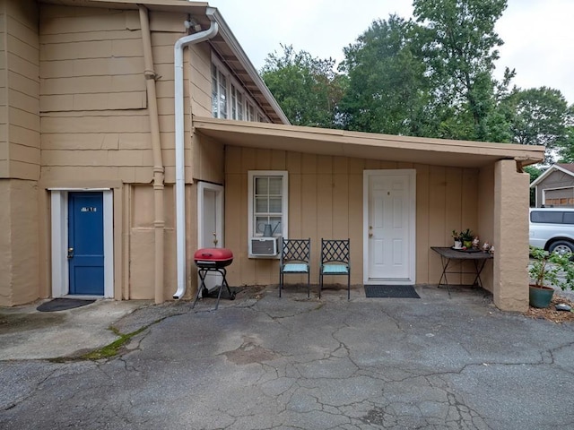 view of exterior entry with a patio and cooling unit