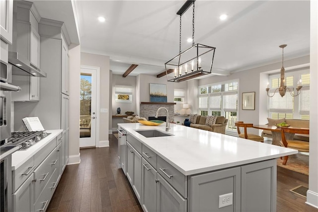 kitchen with decorative light fixtures, sink, gray cabinetry, and a center island with sink