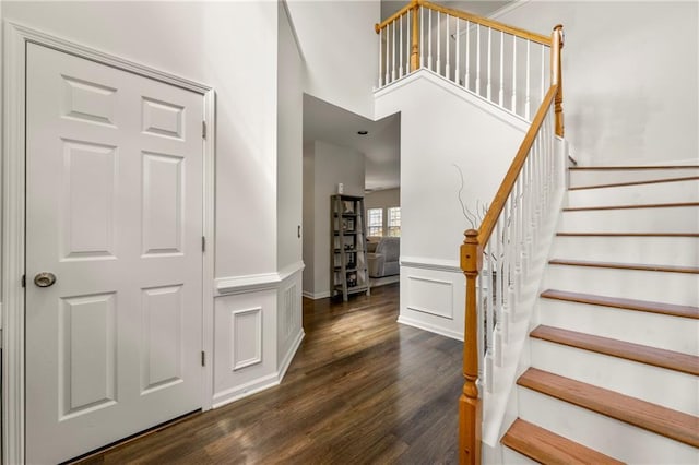 stairway featuring wood-type flooring and a towering ceiling