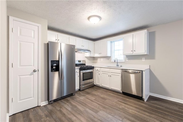 kitchen with dark wood-style flooring, a sink, stainless steel appliances, under cabinet range hood, and white cabinetry