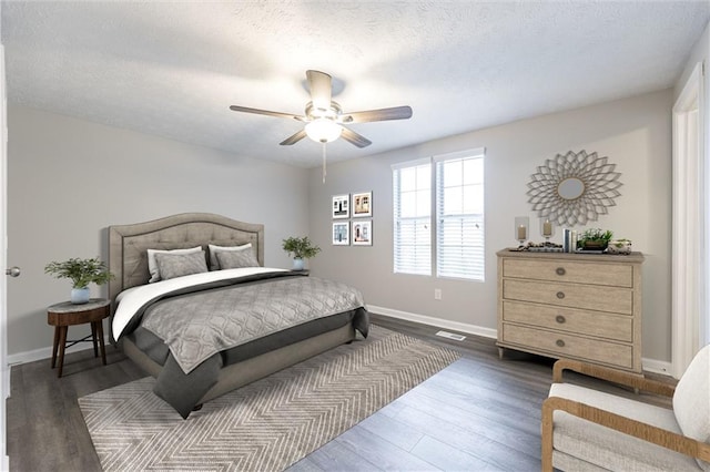 bedroom featuring dark wood finished floors, a textured ceiling, baseboards, and a ceiling fan