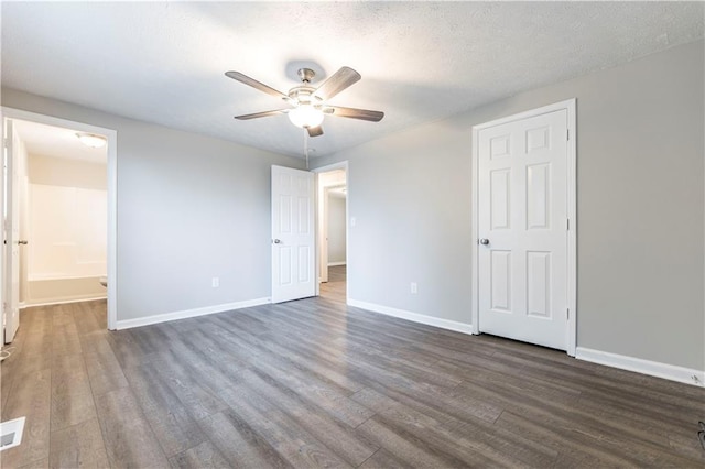 unfurnished bedroom with ensuite bath, wood finished floors, baseboards, and a textured ceiling