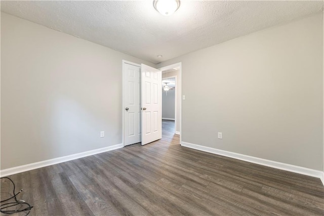 unfurnished room with dark wood-type flooring, baseboards, and a textured ceiling