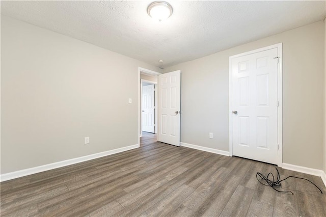 spare room with baseboards, a textured ceiling, and wood finished floors