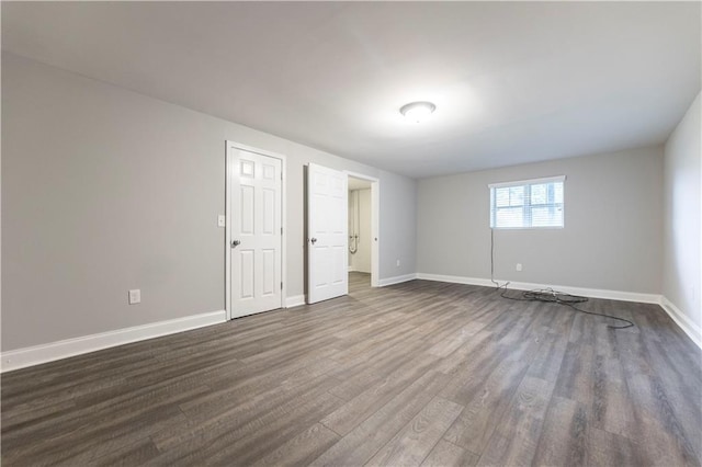 spare room featuring baseboards and dark wood-type flooring