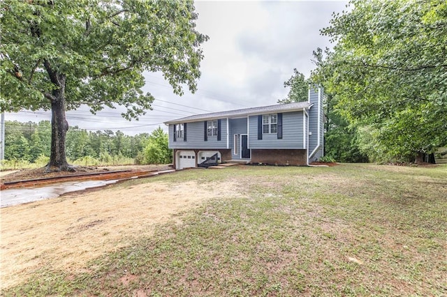 split foyer home with driveway, entry steps, a front yard, a garage, and a chimney