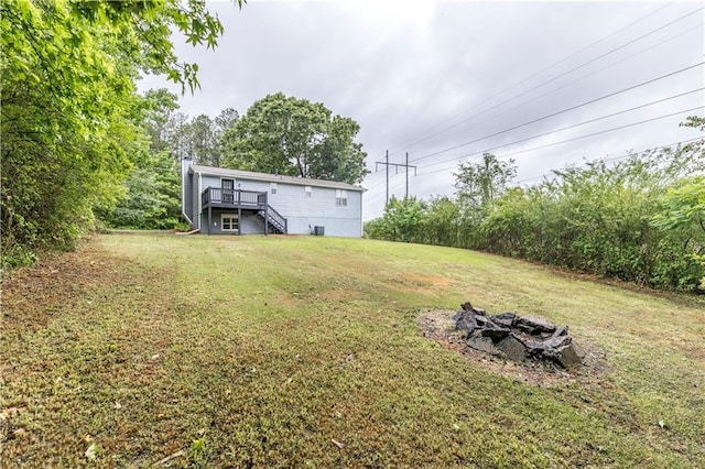 view of yard with stairway, a wooden deck, and an outdoor fire pit