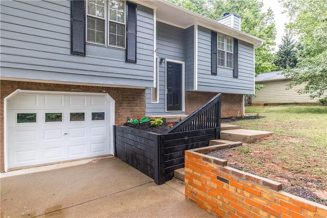 exterior space featuring a garage, brick siding, driveway, and a chimney