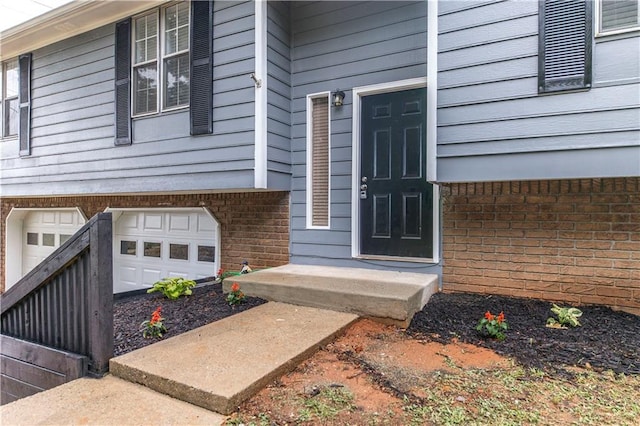 doorway to property featuring brick siding and an attached garage