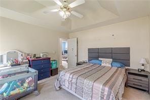 bedroom featuring ceiling fan, a raised ceiling, and light colored carpet