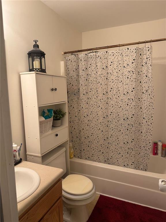 full bathroom featuring vanity, shower / bath combination with curtain, and toilet