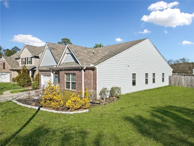 view of home's exterior featuring driveway, fence, a lawn, and brick siding