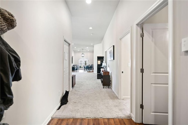 hallway featuring recessed lighting, carpet flooring, baseboards, and wood finished floors