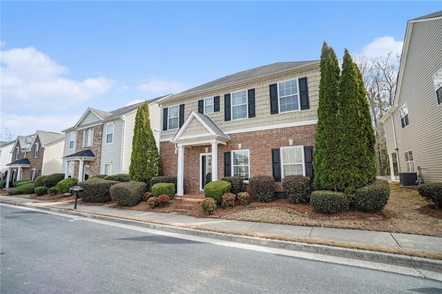 view of front of home with a residential view, brick siding, and central air condition unit