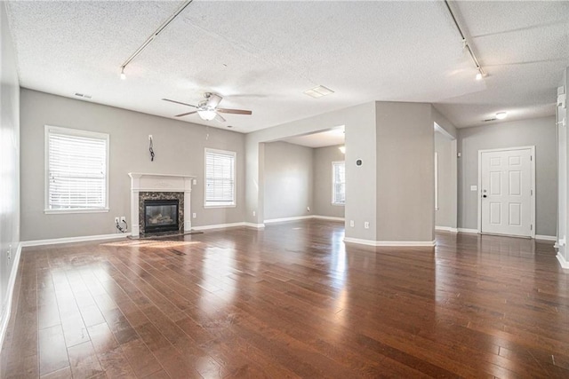 unfurnished living room featuring hardwood / wood-style floors, a ceiling fan, baseboards, a high end fireplace, and a textured ceiling