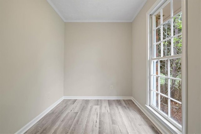 spare room with baseboards, crown molding, and light wood-style floors