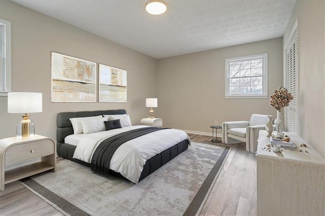 bedroom with baseboards, wood finished floors, and a textured ceiling
