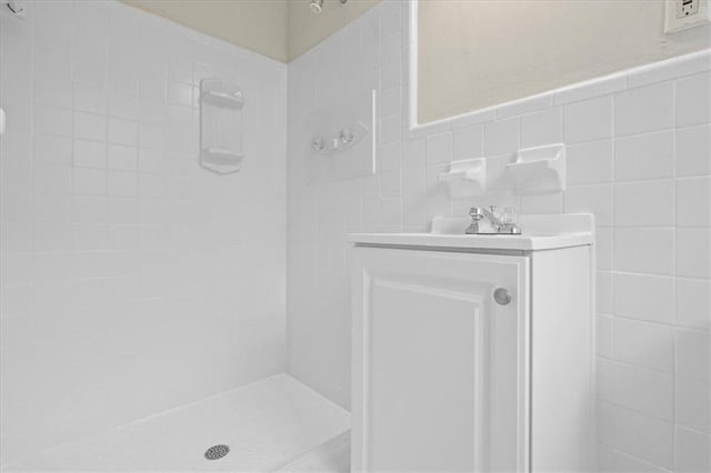 bathroom with tile walls, vanity, and tiled shower