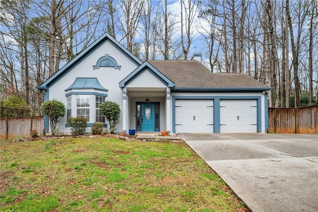 view of front of house featuring a front yard, concrete driveway, fence, and a garage