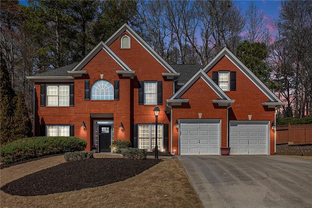 colonial house with concrete driveway, brick siding, and fence