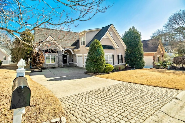 view of front of home with stucco siding, driveway, a front yard, and a garage