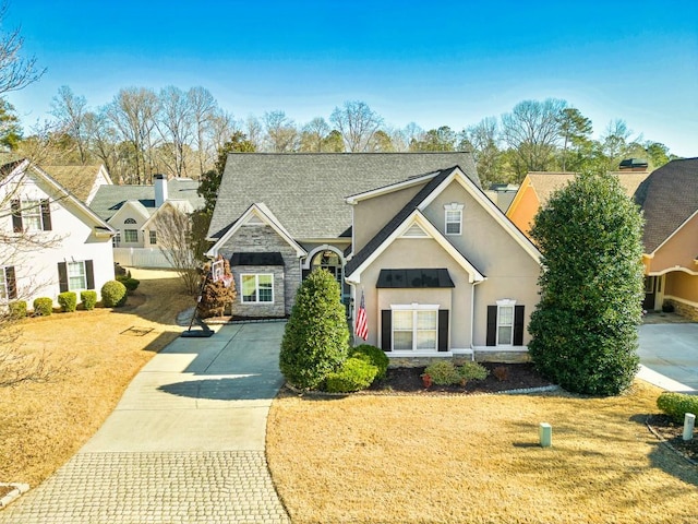 view of front of property featuring stone siding, stucco siding, and a front lawn