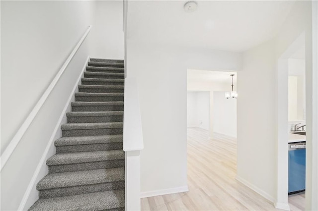 stairs featuring a notable chandelier and wood-type flooring