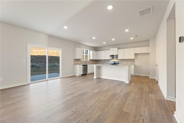 4032 Trimrose Ct, Atlanta, GA 30349 - kitchen with appliances with stainless steel finishes, open floor plan, white cabinetry, recessed lighting, and light wood-style flooring