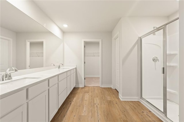4032 Trimrose Ct, Atlanta, GA 30349 - bathroom featuring a shower stall, a spacious closet, wood finished floors, double vanity, and baseboards
