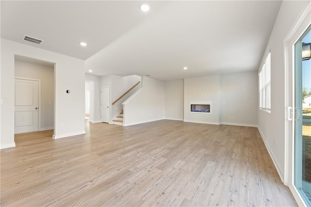 4032 Trimrose Ct, Atlanta, GA 30349 - unfurnished living room featuring stairs, light wood-style flooring, recessed lighting, a glass covered fireplace, and baseboards
