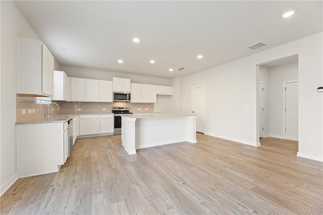 4032 Trimrose Ct, Atlanta, GA 30349 - kitchen with stainless steel appliances, a sink, white cabinetry, backsplash, and a center island