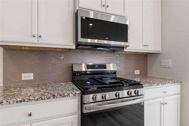 kitchen featuring appliances with stainless steel finishes, light stone counters, hanging light fixtures, and sink