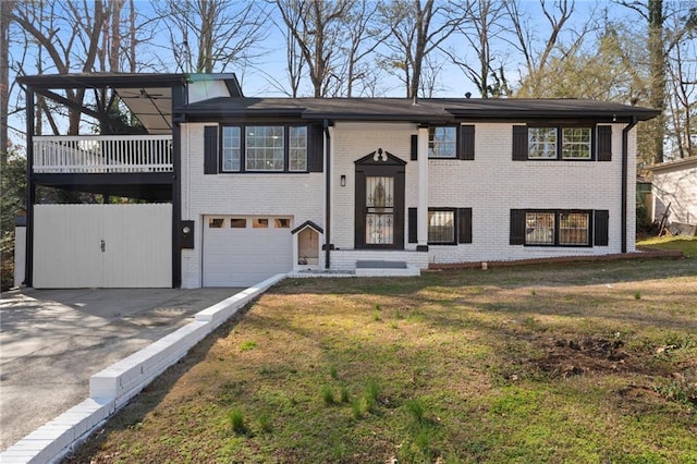 raised ranch featuring aphalt driveway, a front yard, brick siding, and an attached garage